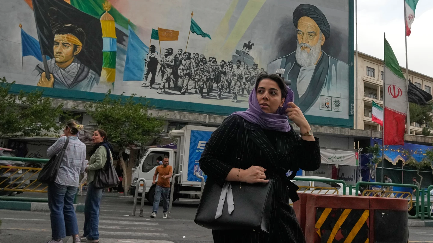 Una mujer cruza la calle frente a un mural del difunto fundador de la revolución iraní, el ayatolá Jomeini, en el centro de Teherán, Irán Una mujer cruza la calle frente a un mural del difunto fundador de la revolución iraní, el ayatolá Jomeini, en el centro de Teherán, Irán