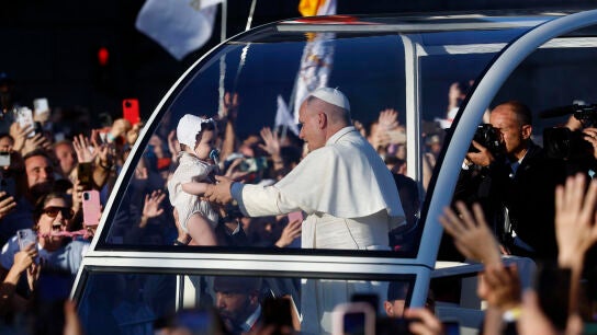 El papa Le&oacute;n XIV coge a un beb&eacute; para bendecirlo durante su trayecto en el papam&oacute;vil