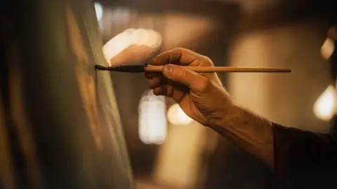 Un pintor pintando a mano un cuadro Un pintor pintando a mano un cuadro