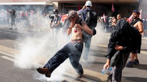 Un manifestante contra el G7 se tapa tras lanzarle un bote de gas lacrim&oacute;geno en Ginebra