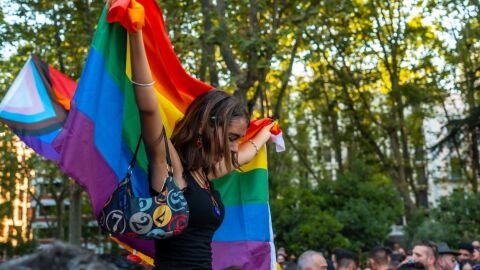 Una asistente alza la bandera del Orgullo entre la multitud