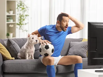 Un hombre viendo el fútbol con su perro al lado Un hombre viendo el fútbol con su perro al lado
