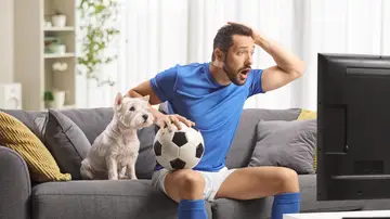 Un hombre viendo el fútbol con su perro al lado Un hombre viendo el fútbol con su perro al lado
