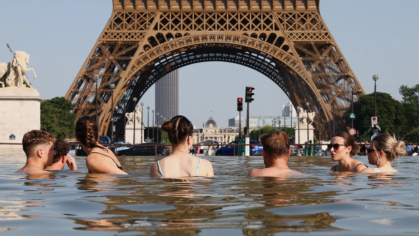 Varias personas se bañan en una fuente frente a la Torre Eifel Varias personas se bañan en una fuente frente a la Torre Eifel