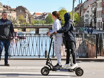 Dos personas montando un patinete eléctrico. Dos personas montando un patinete eléctrico.