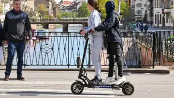 Dos personas montando un patinete eléctrico. Dos personas montando un patinete eléctrico.