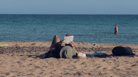 Un hombre lee un libro en la playa Un hombre lee un libro en la playa