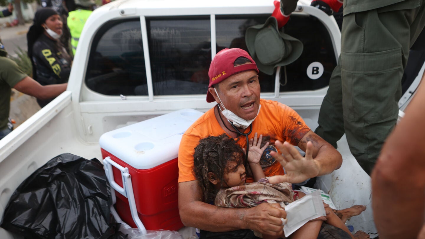 Un rescatista carga a una ni&ntilde;a sacada de entre los escombros en La Guaira