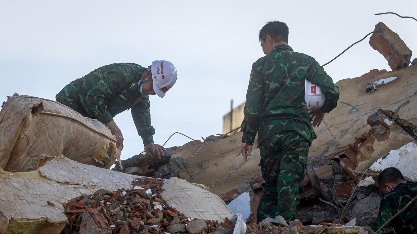 Rescatistas de Vietnam caminan este martes sobre escombros de edificaciones destruidas en Catia La Mar, La Guaira (Venezuela)