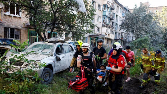 Voluntarios, param&eacute;dicos y rescatistas transportan a un residente herido en el lugar donde un edificio de apartamentos result&oacute; da&ntilde;ado durante los ataques nocturnos con misiles y drones rusos,