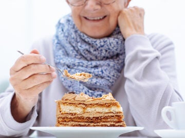 Persona mayor comi&eacute;ndose una tarta