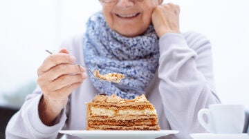 Persona mayor comi&eacute;ndose una tarta