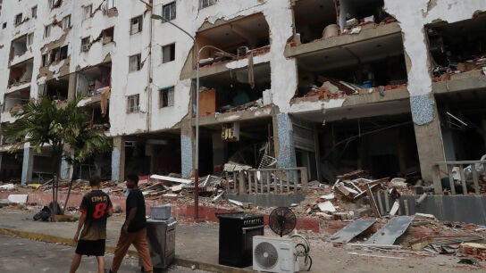 Personas caminan este s&aacute;bado frente a edificios afectados por los terremotos ocurridos en Venezuela
