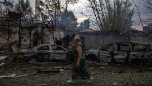 Una mujer camina cerca del lugar de un impacto que incendi&oacute; varios veh&iacute;culos durante ataques rusos con misiles y drones en Kyiv.