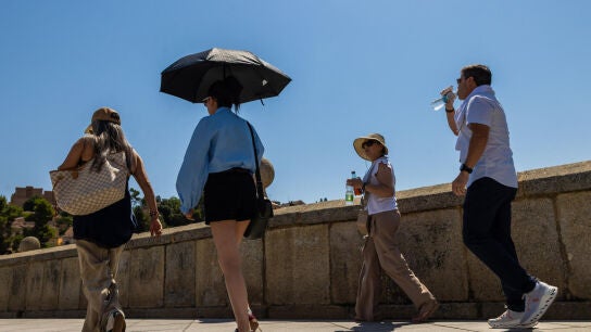 Los turistas se protegen del sol con paraguas y se hidratan este mi&eacute;rcoles en Toledo.