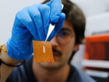 El investigador Yigit Sozen sostiene un chip en un trozo de piel