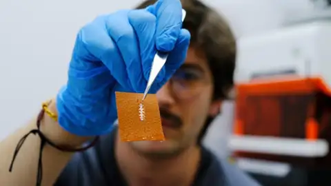 El investigador Yigit Sozen sostiene un chip en un trozo de piel El investigador Yigit Sozen sostiene un chip en un trozo de piel