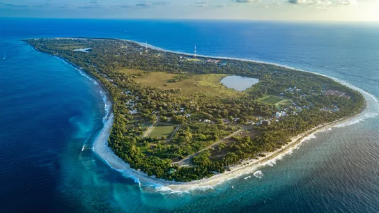 Toma aérea de la isla Fuvahmulah, en Maldivas, rodeada por las vibrantes aguas azules del Océano Índico Toma aérea de la isla Fuvahmulah, en Maldivas, rodeada por las vibrantes aguas azules del Océano Índico