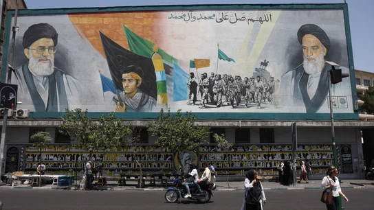 Personas caminan junto a un mural con el ayatolá Ruhollah Khomeini y Ali Jamenei, en una calle de Teherán, Irán Personas caminan junto a un mural con el ayatolá Ruhollah Khomeini y Ali Jamenei, en una calle de Teherán, Irán