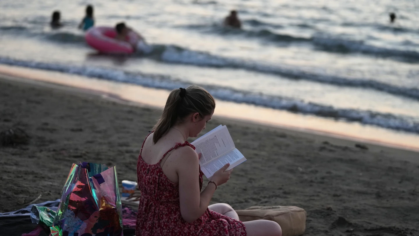 Una mujer lee un libro en la playa de Kavouri, al sur de Atenas, Grecia Una mujer lee un libro en la playa de Kavouri, al sur de Atenas, Grecia
