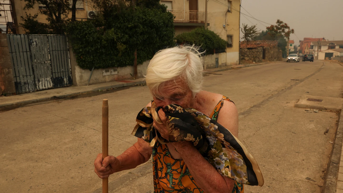 Juana González, residente de la localidad de El Tiemblo, se cubre el rostro para protegerse del humo durante un incendio forestal que afecta a la provincia de Castilla y León Juana González, residente de la localidad de El Tiemblo, se cubre el rostro para protegerse del humo durante un incendio forestal que afecta a la provincia de Castilla y León