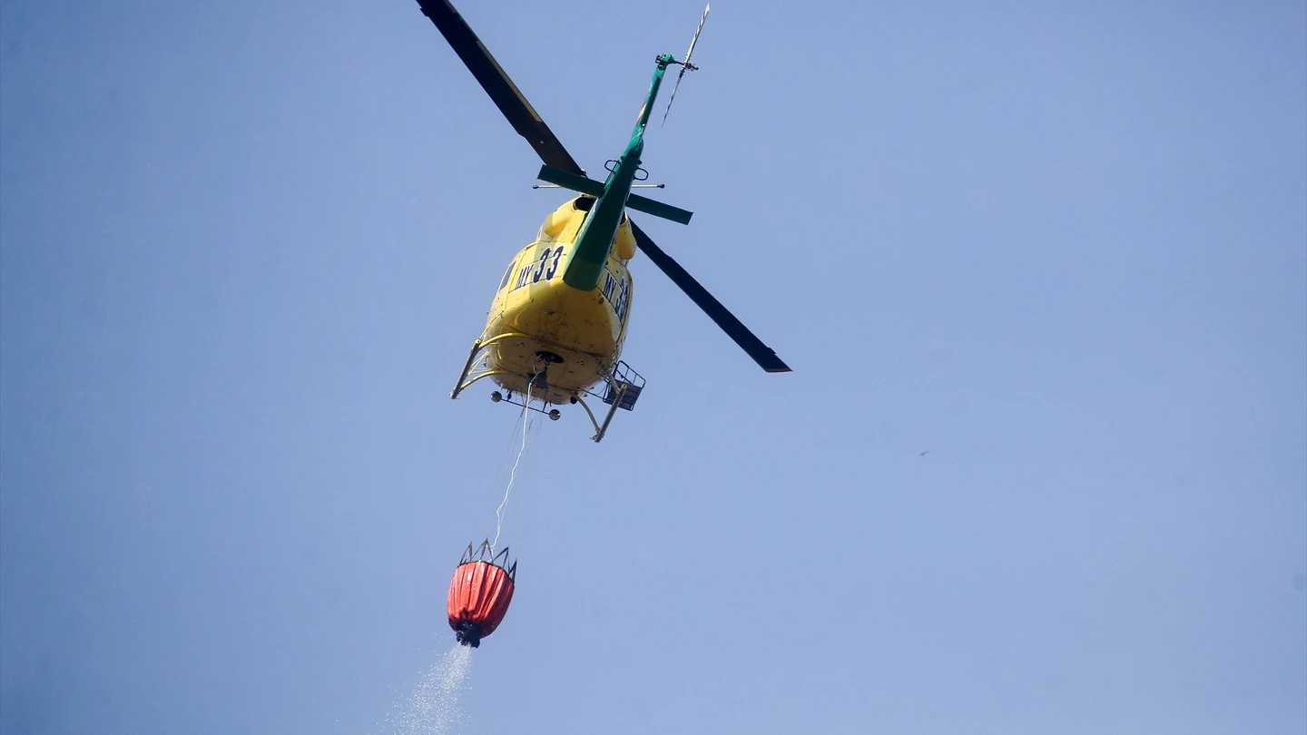 Un helicóptero trabaja en las labores de extinción de un fuego Un helicóptero trabaja en las labores de extinción de un fuego