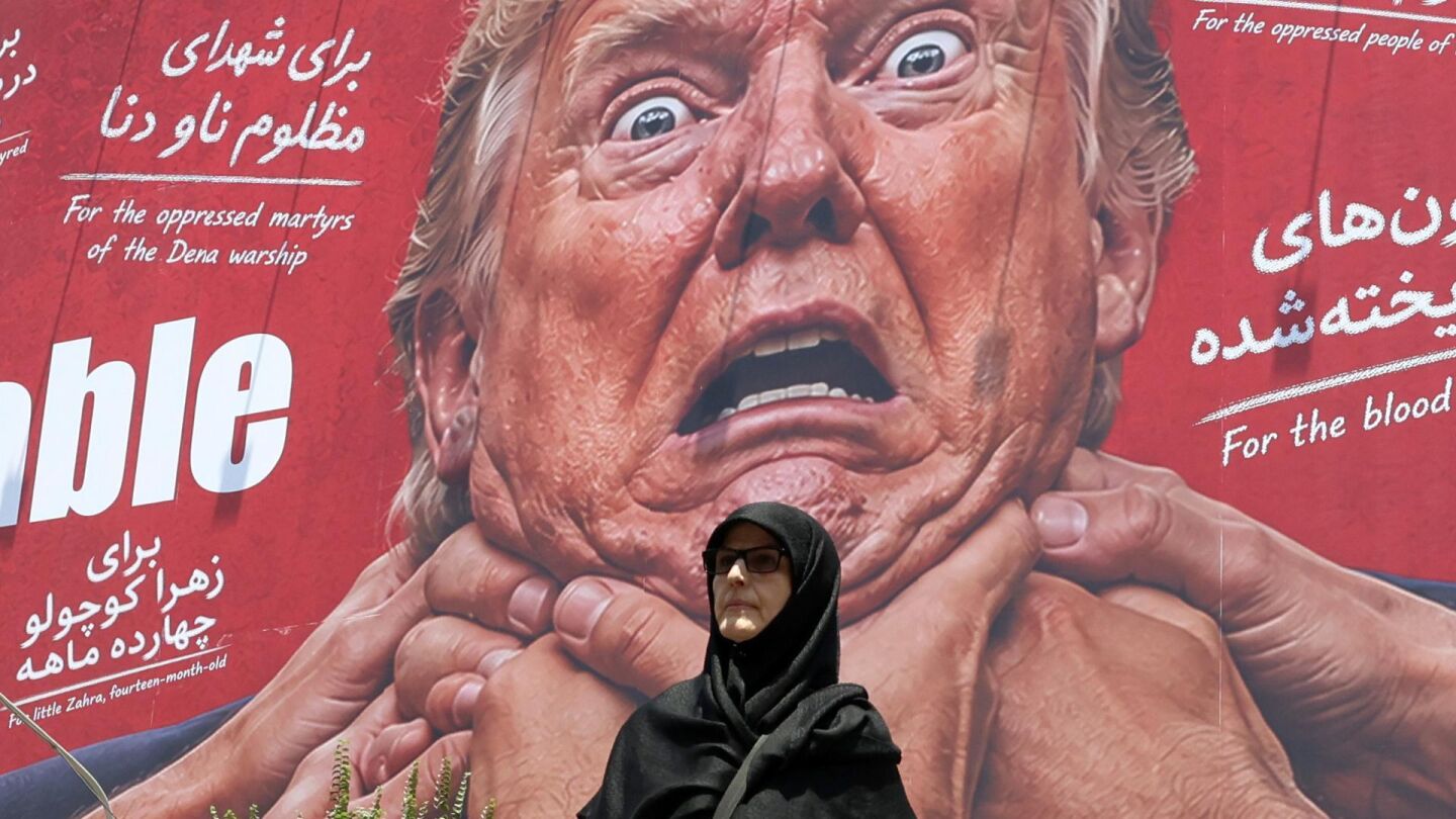 Una mujer pasa junto a una valla publicitaria antiestadounidense y anti-Trump en una calle de Teher&aacute;n, Ir&aacute;n.