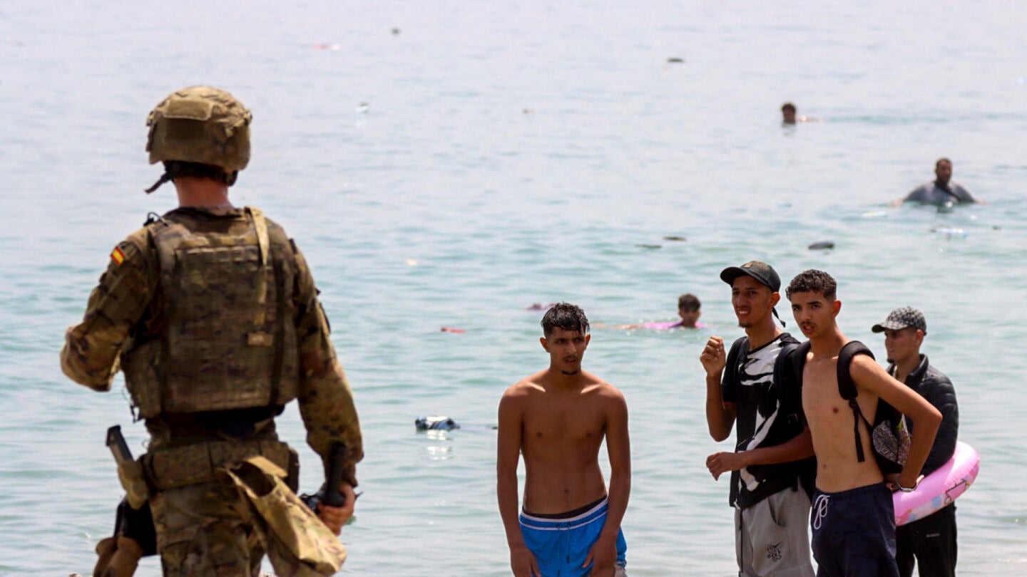 Un militar, frente a varios migrantes