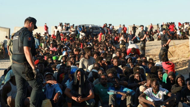 Migrantes hacen fila para recibir alimentos y bebidas de la Cruz Roja, tras los cruces masivos de migrantes en Ceuta