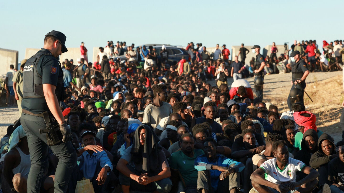 Migrantes hacen fila para recibir alimentos y bebidas de la Cruz Roja, tras los cruces masivos de migrantes en Ceuta