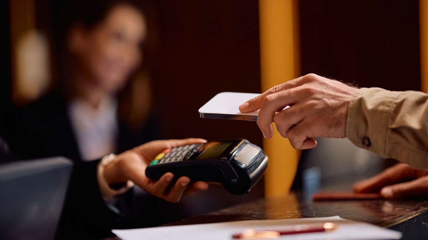 Hombre pagando en la recepci&oacute;n de un hotel