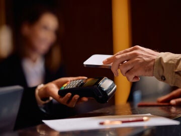 Hombre pagando en la recepci&oacute;n de un hotel
