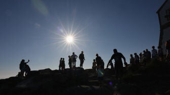 Turistas caminan por el cabo Fisterra el d&iacute;a antes del eclipse solar, en la Costa de la Muerte