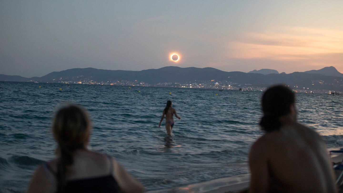 Una mujer ba&ntilde;&aacute;ndose en el mar durante el eclipse total del 12 de agosto de 2026 en una playa en Palma de Mallorca
