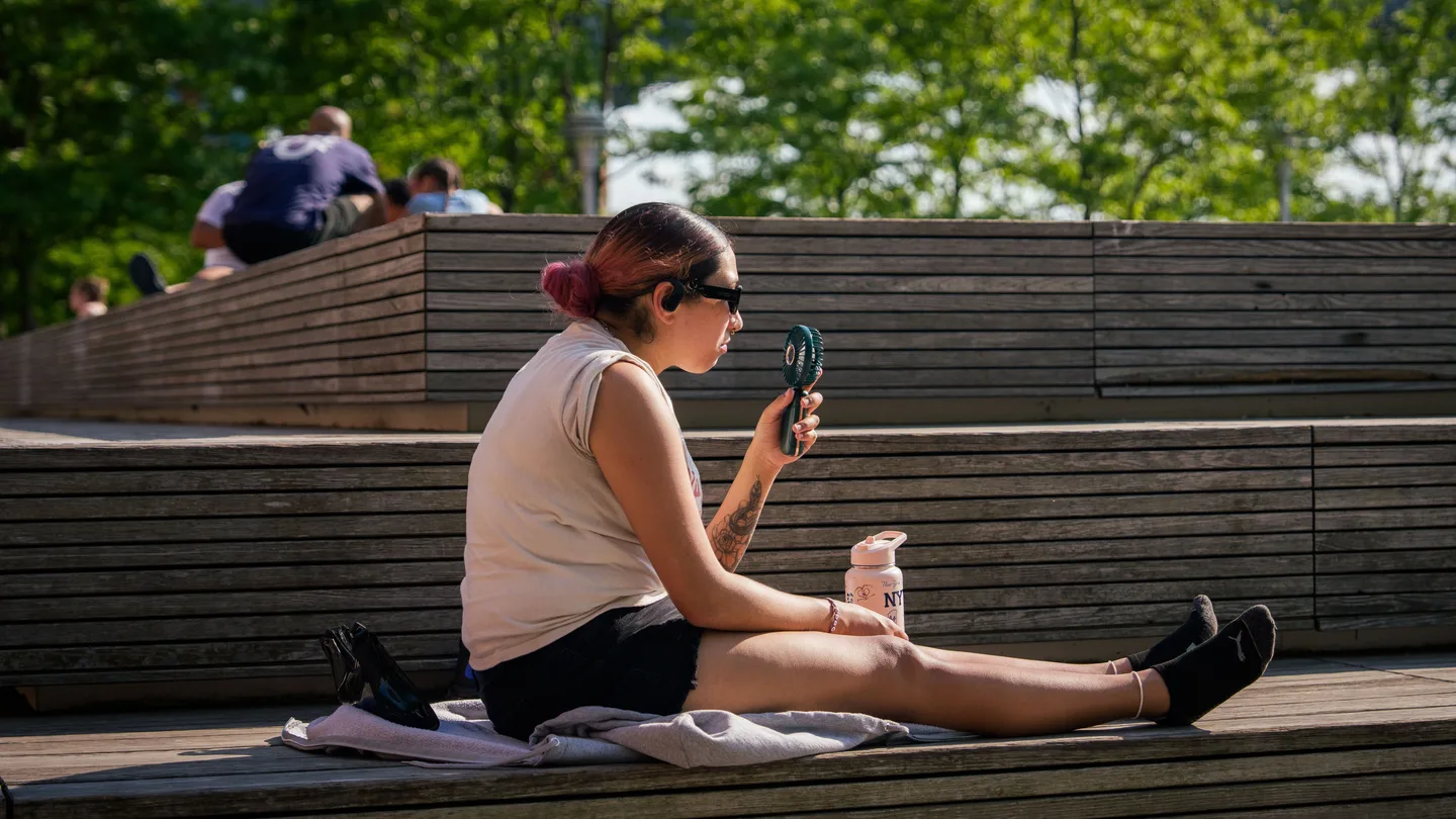 Una mujer usa un ventilador portátil durante una alerta por calor. Una mujer usa un ventilador portátil durante una alerta por calor.