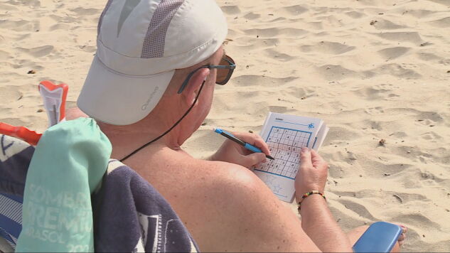 Un hombre hace un sudoku en la playa