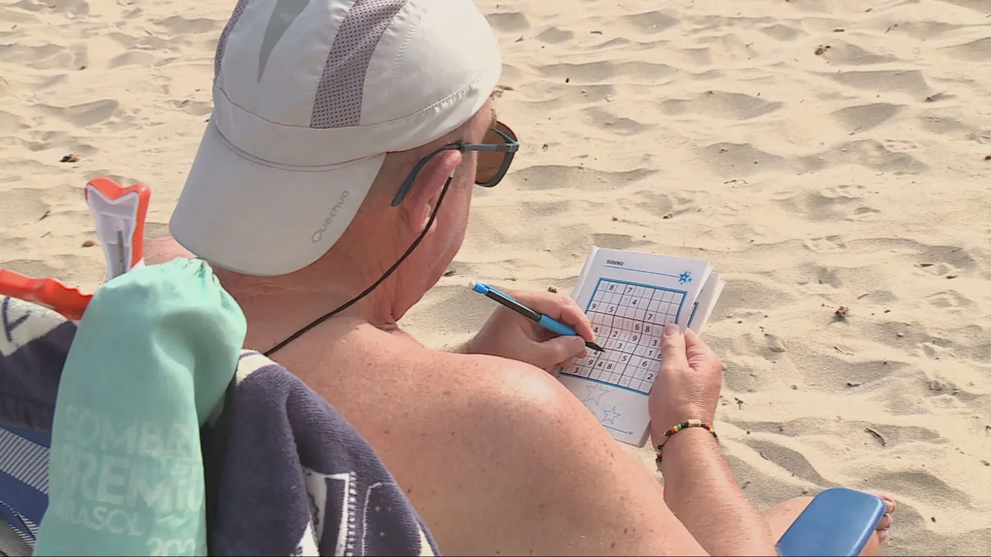 Un hombre hace un sudoku en la playa Un hombre hace un sudoku en la playa