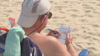 Un hombre hace un sudoku en la playa