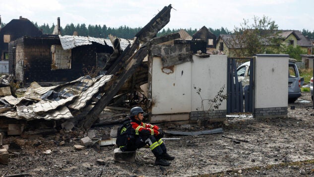 Un rescatista descansa en los escombros de una casa en Kyiv