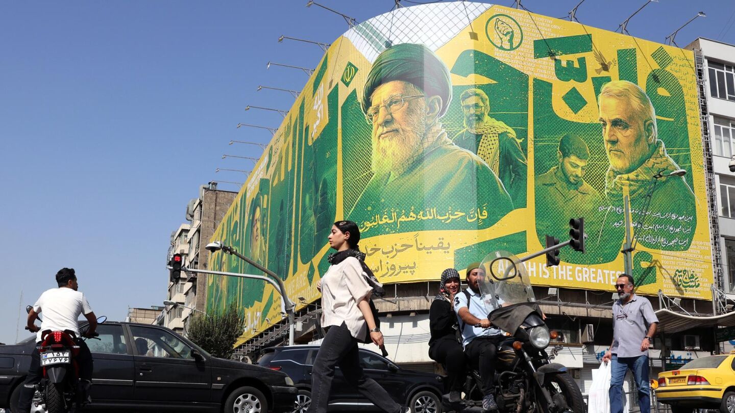 Imagen de archivo. Iran&iacute;es transita ante una valla publicitaria en Teher&aacute;n que representa al exl&iacute;der de Hizbul&aacute;, Has&aacute;n Nasrala, al difunto l&iacute;der supremo iran&iacute;, Al&iacute; Jamene&iacute;