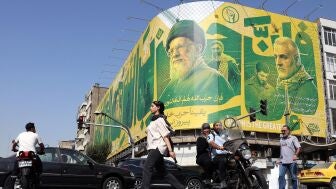 Imagen de archivo. Iran&iacute;es transita ante una valla publicitaria en Teher&aacute;n que representa al exl&iacute;der de Hizbul&aacute;, Has&aacute;n Nasrala, al difunto l&iacute;der supremo iran&iacute;, Al&iacute; Jamene&iacute;