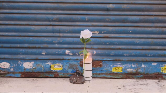 Una flor y una vela frente al negocio del fallecido en L'Hospitalet de Llobregat.