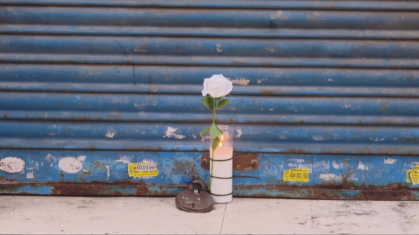Una flor y una vela frente al negocio del fallecido en L'Hospitalet de Llobregat.