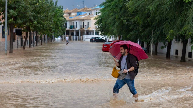 Un hombre camina en una calle convertida en un r&iacute;o en Murcia