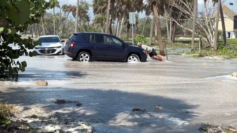 Un hombre trata de empujar su coche en Florida tras el paso del hurac&aacute;n Isaias