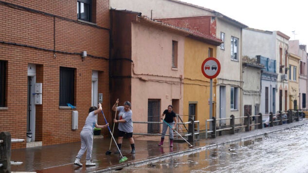 Varios vecinos, quitando el agua de las aceras