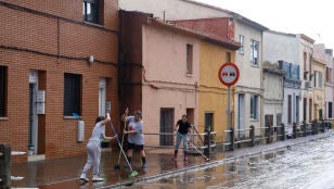 Varios vecinos, quitando el agua de las aceras