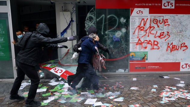 Varias personas salen por el escaparate roto de una tienda para evacuar el edificio, durante los enfrentamientos posteriores a una manifestaci&oacute;n en Par&iacute;s