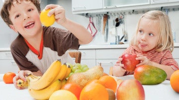 Dos niños comiendo fruta