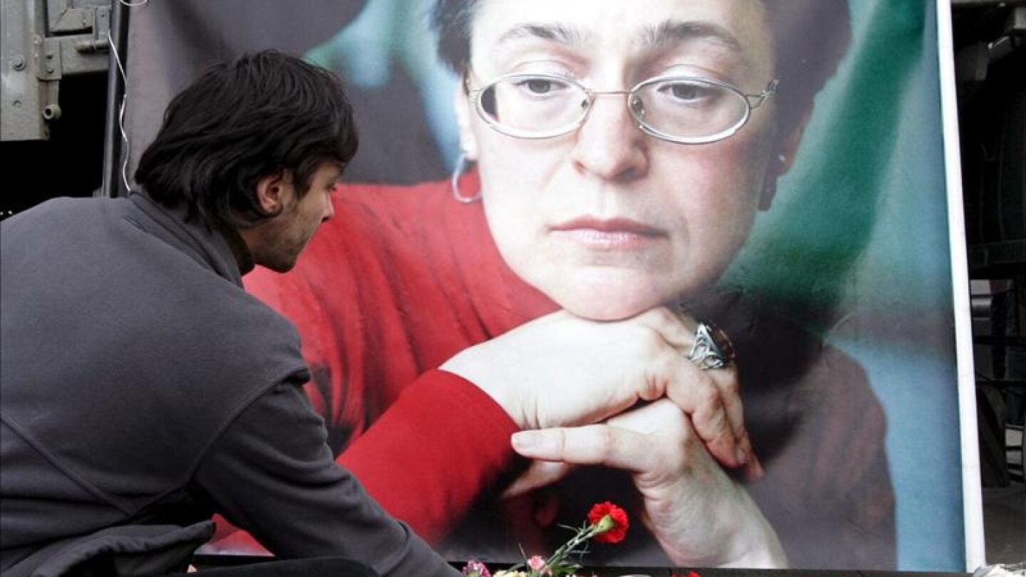Un hombre deposita flores delante de un retrato de la periodista rusa Anna Politk&oacute;vskaya